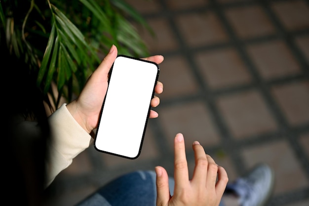 Closeup image of an Asian woman using her phone at the backyard smartphone mockup