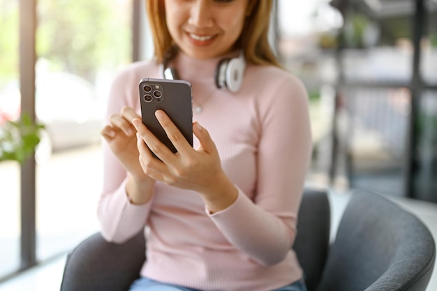 Closeup image of an Asian woman using her smartphone while resting in the coffee shop