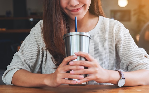 Closeup image of a beautiful asian woman drinking coffee in stainless steel cup