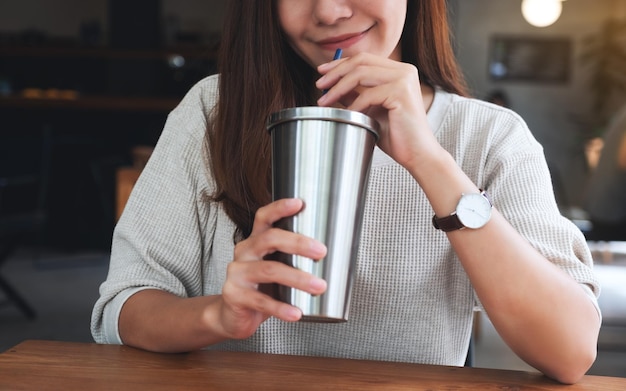 Closeup image of a beautiful asian woman drinking coffee in stainless steel cup