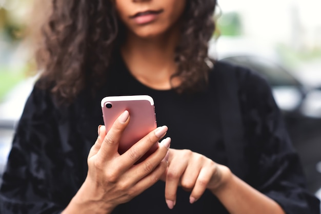 closeup image of a beautiful mixed race woman holding using and looking at her smart phone