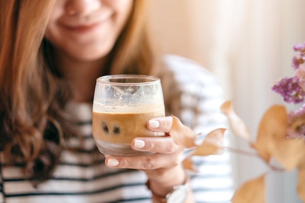 Closeup image of a beautiful woman holding a glass of iced coffee to drink in cafe