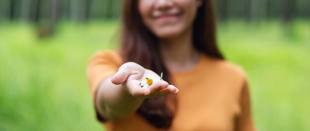 Closeup image of a beautiful young asian woman holding and giving a Biden Alba or Spanish needles flower