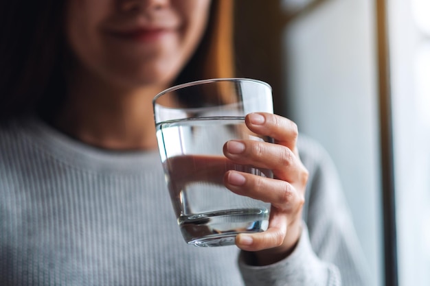 Closeup image of a beautiful young asian woman holding a glass of water to drink