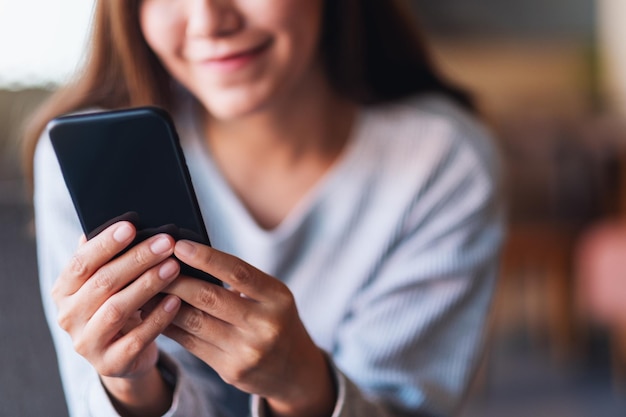 Closeup image of a beautiful young asian woman holding and using mobile phone