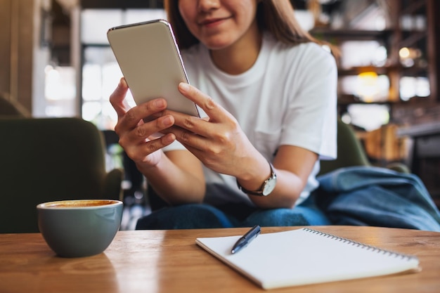 Closeup image of a beautiful young asian woman holding and using mobile phone