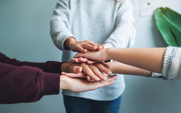 Closeup image of business team standing and joining their hands together in office