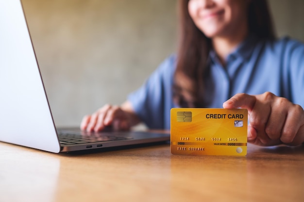 Closeup image of a business woman holding and showing a credit cards while using laptop computer for online payment