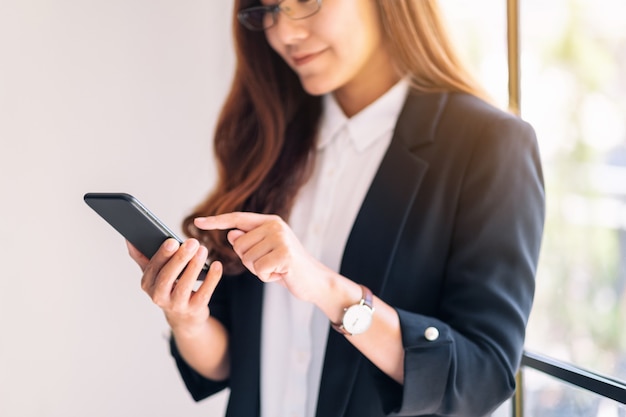 Closeup image of a businesswoman holding and using mobile phone