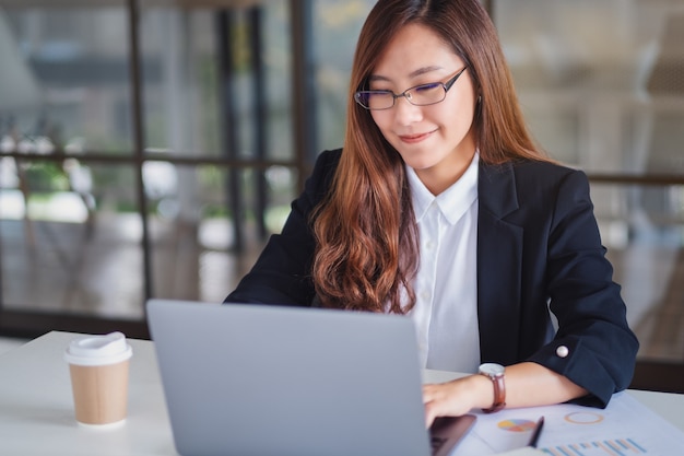 Closeup image of businesswoman using and typing on laptop while working in office