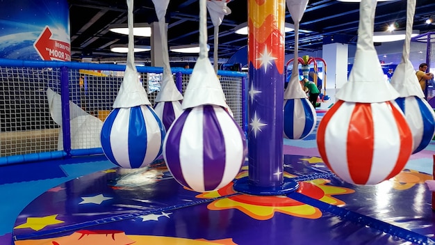 Closeup image of colorful chidlren carousel and swing on the playground covered with soft mats for children safety