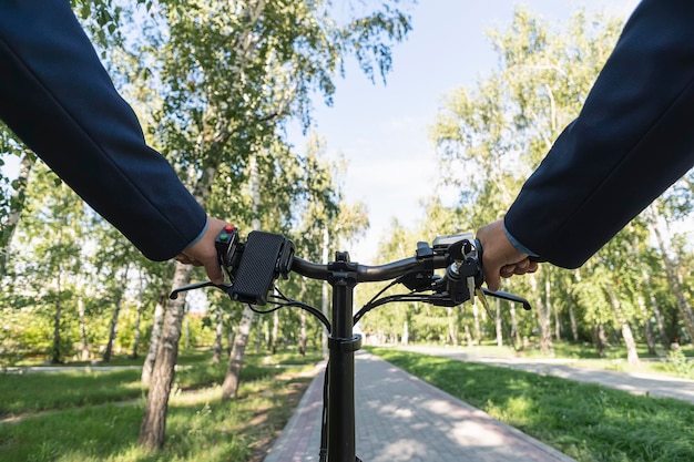 Closeup image of cyclist man hands on handlebar riding electric bike in park face is not visibleYoung man riding bike in city park View from bikers eyes