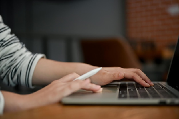 Closeup image of a female freelancer using her laptop in a coffee shop