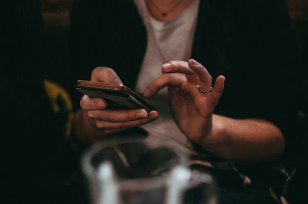 Closeup image of female hands using smartphone in cafe in the evening social networks