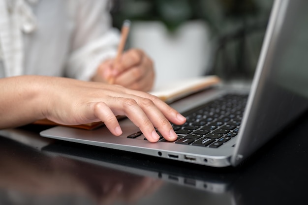 A closeup image of a female student typing on her laptop keyboard while studying online