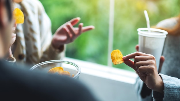 Closeup image of friends drinking and eating potato chips together