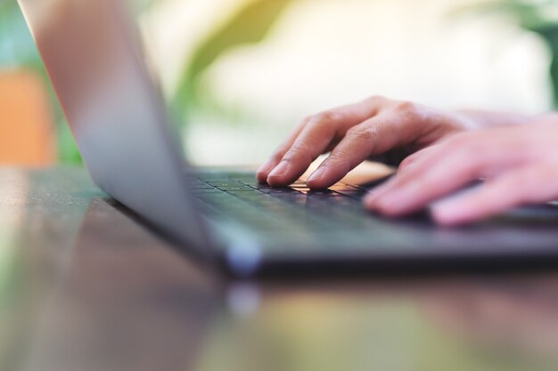 Photo closeup image of hands using and typing on laptop computer keyboard on the table