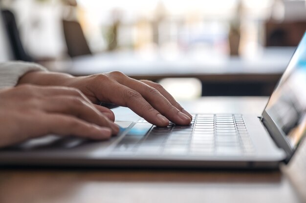 Photo closeup image of hands using and typing on laptop keyboard on the table