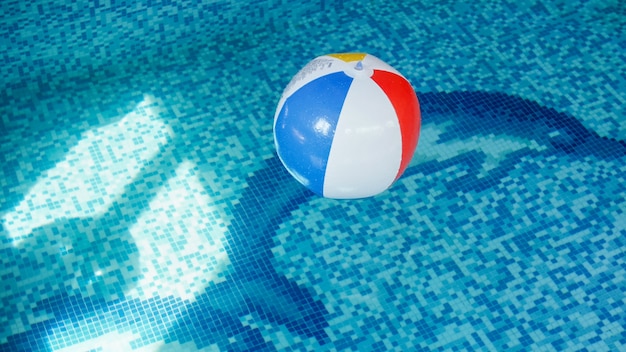 Closeup image of inflatable beach ball in swimming pool. Perfect image to illustrate summer beach vacation on holidays