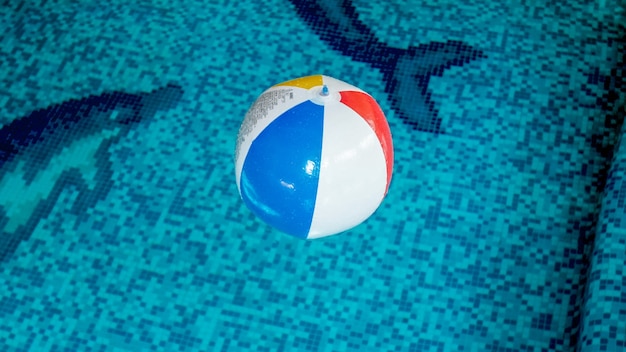 Closeup image of inflatable beach ball in swimming pool. Perfect image to illustrate summer beach vacation on holidays