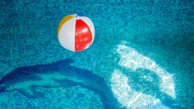 Closeup image of inflatable beach ball in swimming pool. Perfect image to illustrate summer beach vacation on holidays