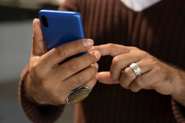 Closeup image of male hands with rings on their fingers typing messages on the social network using a blue smart phone concept Technology