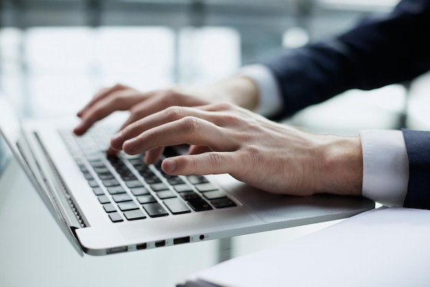 Closeup image of a man working and typing on laptop computer keyboard