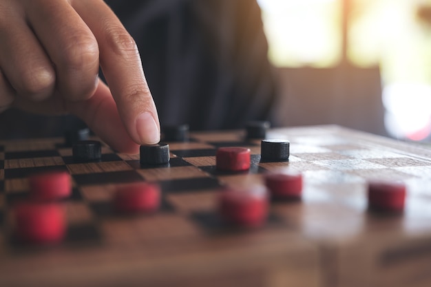 Closeup image of people playing and moving checkers in a chessboard