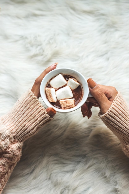 Closeup image A tasty hot melted chocolate with tiny marshmallows cup in a woman's hand