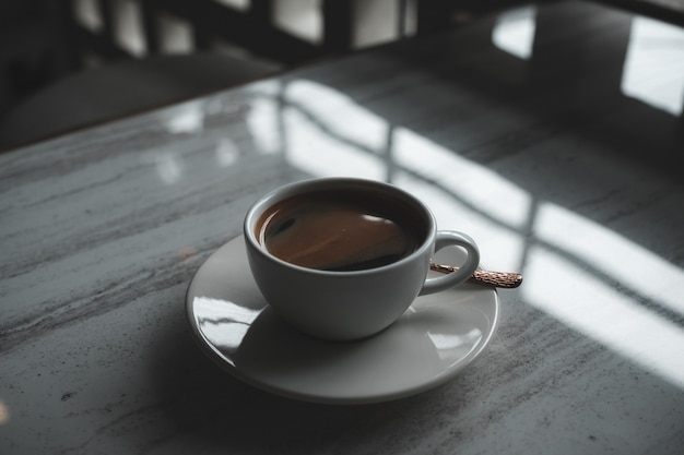 Closeup image of a white cup of hot coffee on table