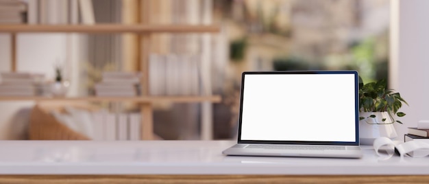 Closeup image of a whitescreen laptop computer and accessories on a wooden desk in a modern room