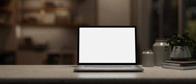 A closeup image of a whitescreen laptop computer mockup on a desk in a modern dark room at night