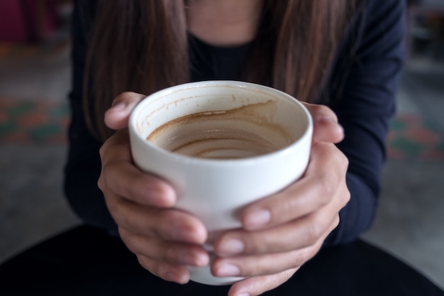 Closeup image of a woman holding a cup of coffee in cafe