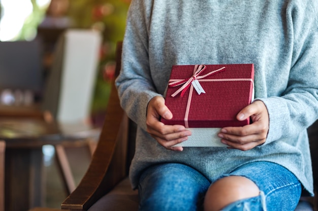 Closeup image of a woman holding a red present box