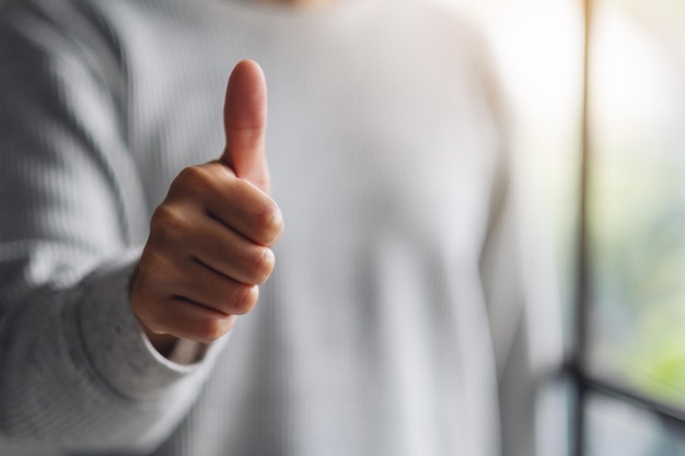 Closeup image of a woman making and showing thumbs up hand sign