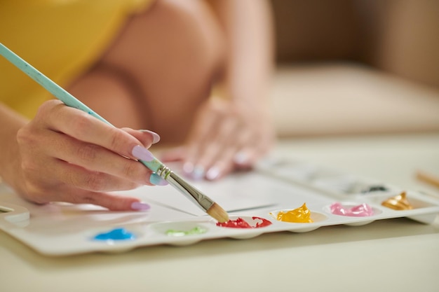 Closeup image of woman painting pictures at home to decorate house