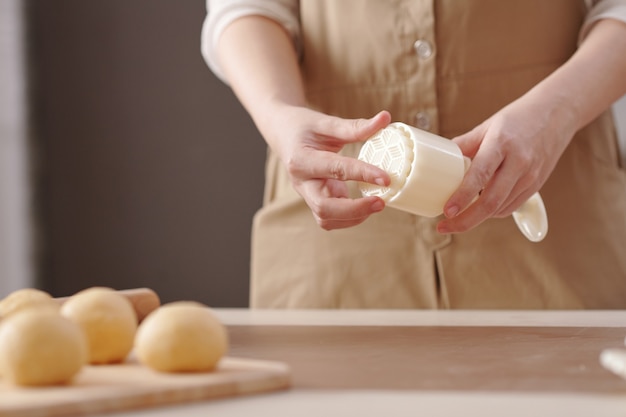 Closeup image of woman preparing plastic form for making mooncakes for mid autumn season