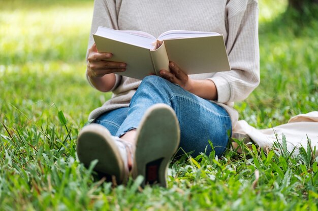 Closeup image of a woman reading a book while sitting in the park