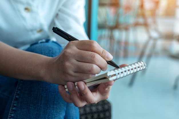 Closeup image of a woman's hands holding and writing on blank notebook