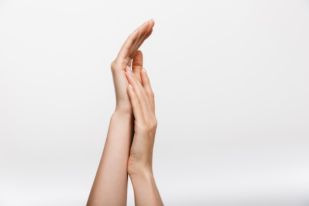 Closeup image of woman's hands isolated over white wall wall touching each other.