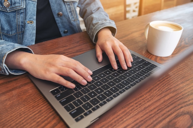 Closeup image of woman's hands using and typing on laptop keyboard on the table