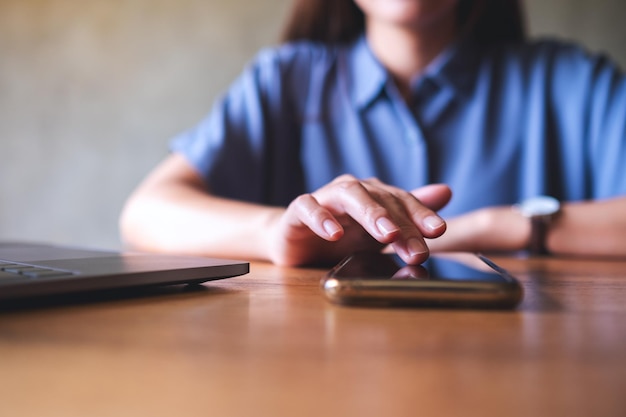 Closeup image of a woman using mobile phone and laptop computer