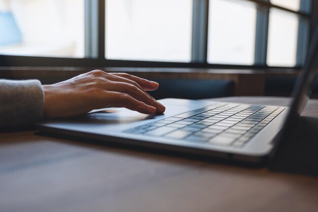 Photo closeup image of a woman working and touching on laptop computer touchpad on the table