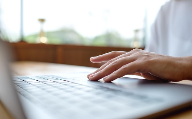 Photo closeup image of a woman working and touching on laptop computer touchpad