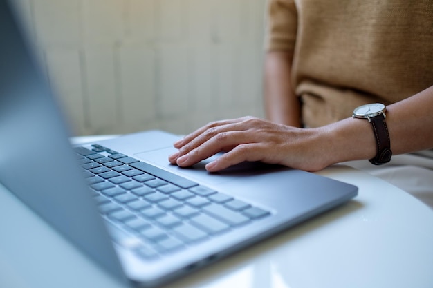 Closeup image of a woman working and touching on laptop touchpad on the table