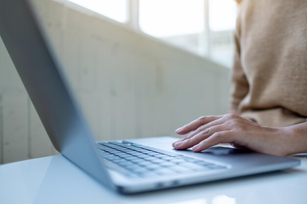 Closeup image of a woman working and touching on laptop touchpad on the table