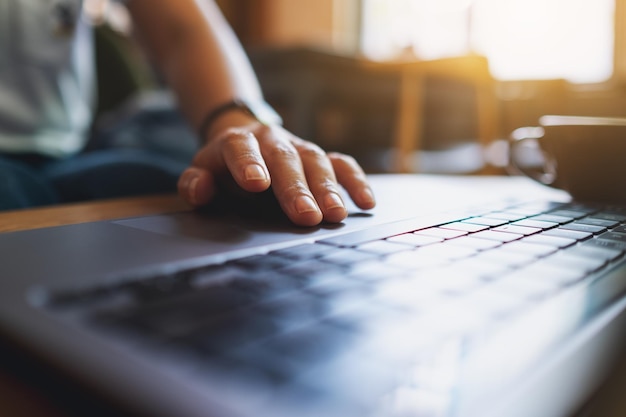 Closeup image of a woman working and touching on laptop touchpad on the table