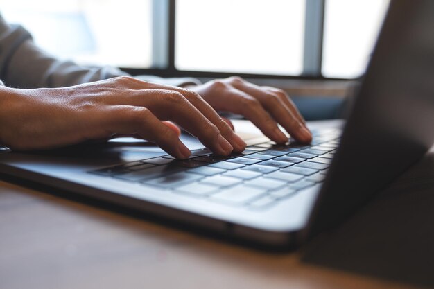 Photo closeup image of a woman working and typing on laptop computer keyboard on the table