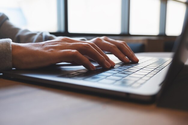 Photo closeup image of a woman working and typing on laptop computer keyboard on the table