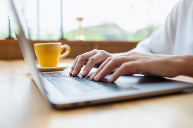 Photo closeup image of a woman working and typing on laptop computer keyboard on the table